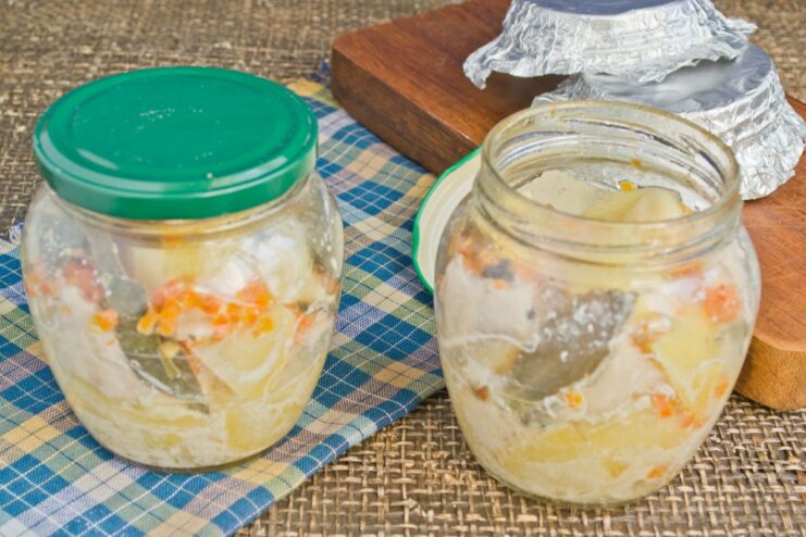 The Cooking Process: Jars of Chicken and Potatoes Baking in the Oven Several jars of chicken and potatoes baking on a rack inside a lit oven.