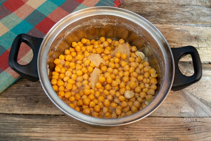 A pot of chickpeas boiling in water on a stove, the first step for making falafel.