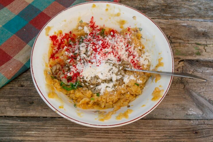Flour, paprika, and salt being added to the falafel mixture in a glass bowl.