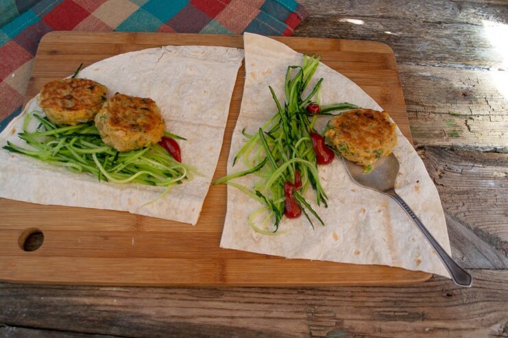 Assembling a falafel wrap: sliced cucumber and falafel patties on a piece of lavash flatbread.