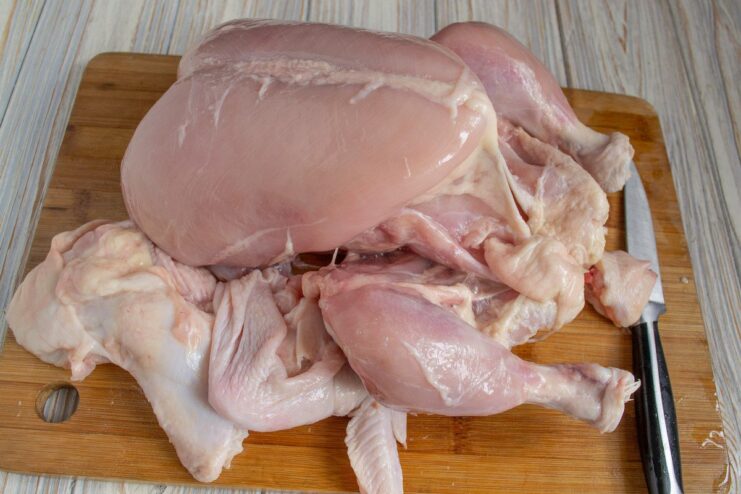 How to carefully separate the chicken skin while keeping it intact Hands carefully pulling the skin off a raw chicken carcass, with the wings still attached to the skin.
