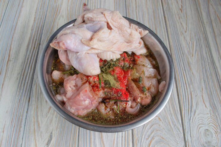 Marinating the chicken meat and skin for maximum flavor A bowl containing raw chicken meat and skin mixed with herbs and marinade.