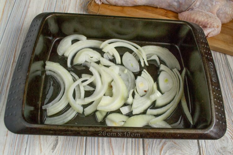 Creating a flavorful base of onions for the chicken to roast on A baking dish with a layer of sliced onions on the bottom.