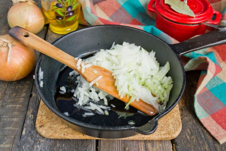 Sautéing Onions for the Stuffed Pepper Filling Finely chopped onions being sautéed in a pan with oil until translucent.