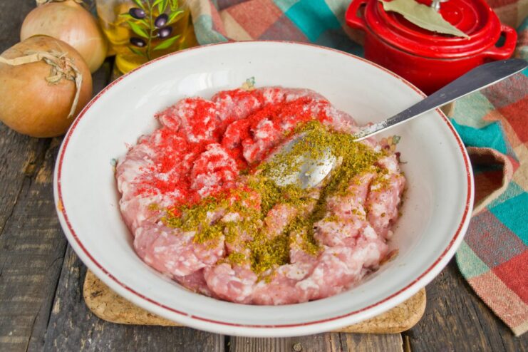 Seasoning the Minced Meat with Spices Spices like paprika and a meat seasoning blend being added to the bowl of minced meat.