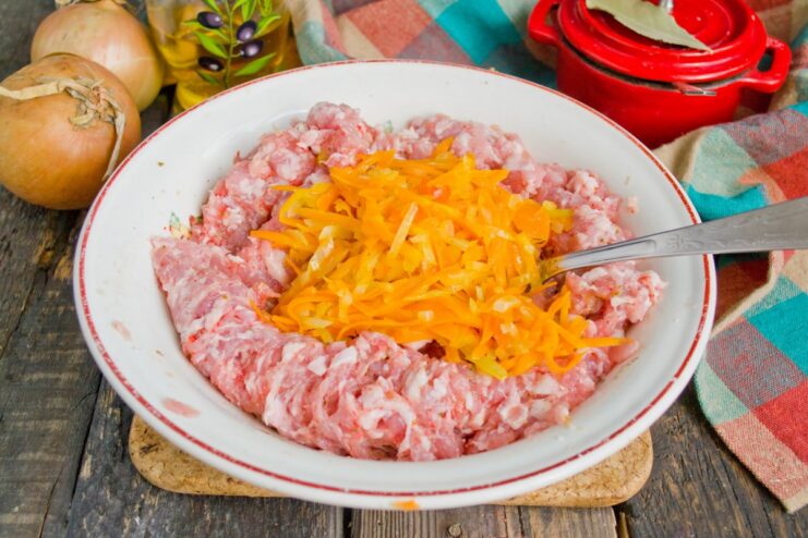 Mixing Sautéed Vegetables into the Minced Meat Sautéed onions and carrots being mixed into the seasoned minced meat in a bowl.
