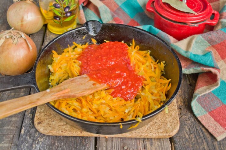 Making the Tomato Sauce Base Tomato purée being added to the remaining sautéed onions and carrots in a pan to create a sauce.