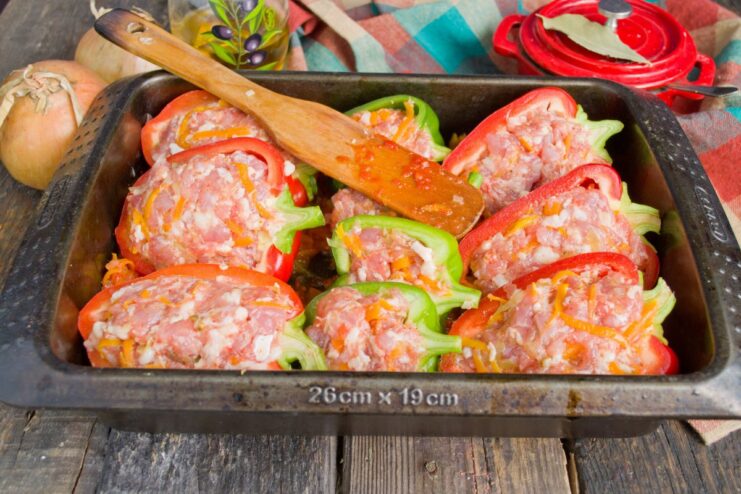 Assembling the Stuffed Peppers in a Baking Dish Stuffed pepper halves arranged snugly over a layer of tomato and vegetable sauce in a baking dish.