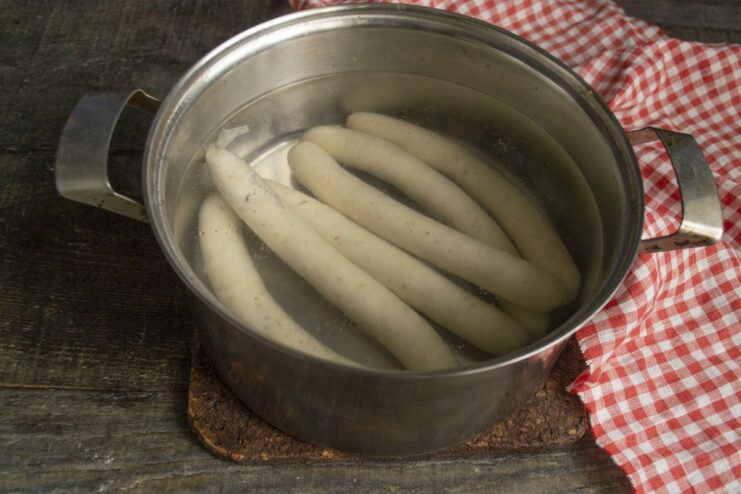How to Parboil Sausages to Prevent Splitting Sausages being placed into a pot of boiling water with tongs.