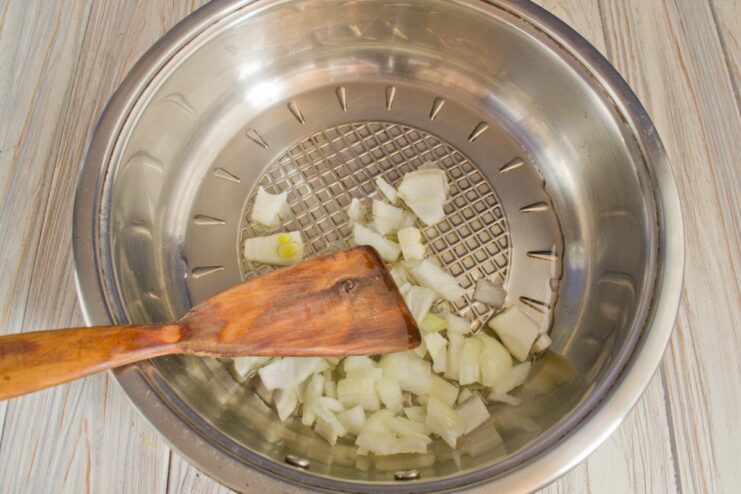 Sautéing Onions for the Fricassee Base Finely chopped onions being sautéed in a skillet until translucent.