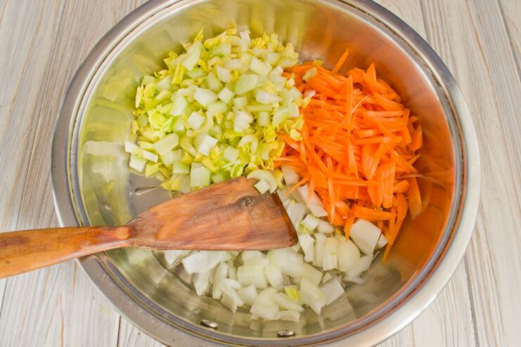 Cooking the Vegetable Base for the Fricassee A mix of chopped onions, carrots, and celery being sautéed in a skillet.