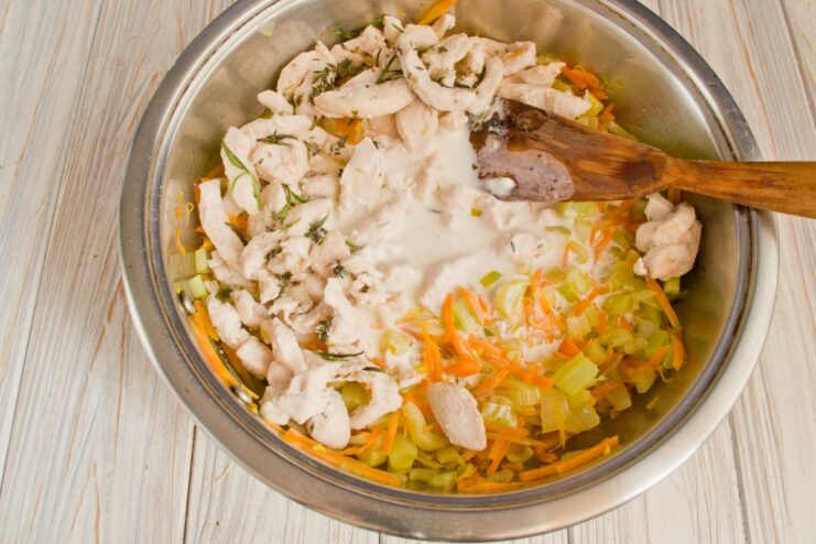 Creating the Creamy Sauce for the Fricassee A creamy white sauce mixture being poured from a bowl into the skillet with chicken and vegetables.