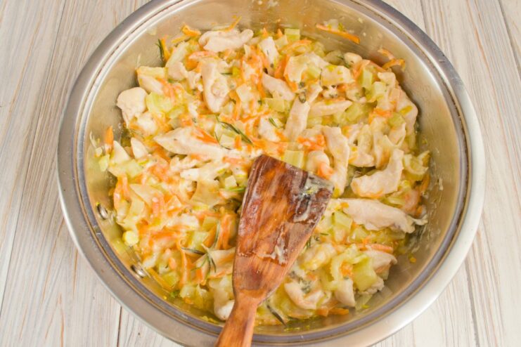 Simmering the Fricassee to Thicken the Sauce Chicken and vegetables simmering in a creamy white sauce in a skillet, being stirred.
