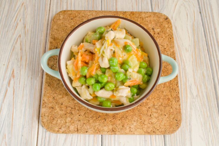 Ready to Serve Chicken Fricassee with Peas A serving of creamy chicken fricassee with green peas in a white bowl, ready to eat.