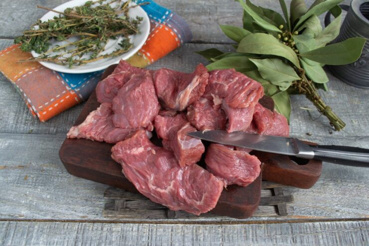 Slicing beef tenderloin against the grain for maximum tenderness. A piece of beef tenderloin being sliced into thick pieces on a cutting board.