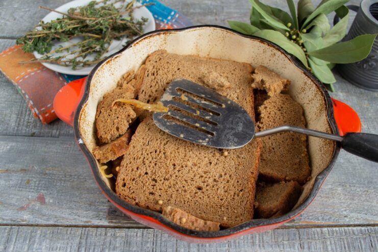 Creating a unique topping with slices of dark Borodinsky rye bread. The surface of the beef stew being completely covered with slices of dark Borodinsky bread.
