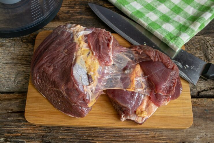 Preparing the Beef for Grinding Chunks of raw beef on a cutting board, ready to be minced.