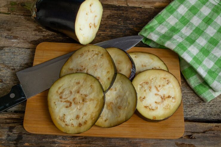 Slicing and Salting the Eggplant Thick round slices of eggplant on a surface, sprinkled with salt.