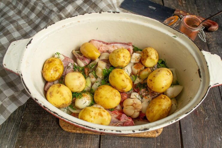 Building the Stew: Adding a Layer of Potatoes Whole new potatoes being layered over the seasoned beef ribs in the pot.