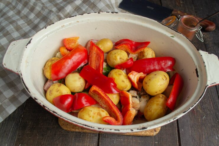 Adding Color and Sweetness with Bell Peppers Pieces of red bell pepper layered on top of potatoes in the braiser.