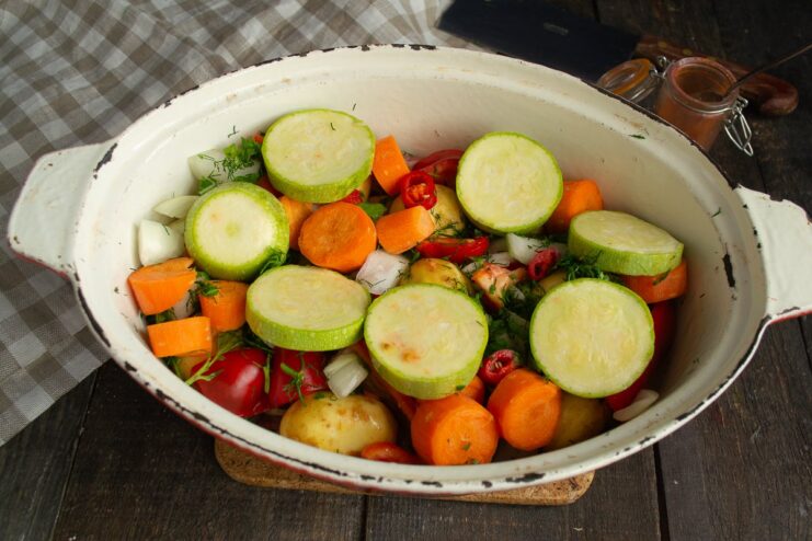 Final Vegetable Layer: Adding Zucchini Thick slices of zucchini being layered over other vegetables in the braiser.