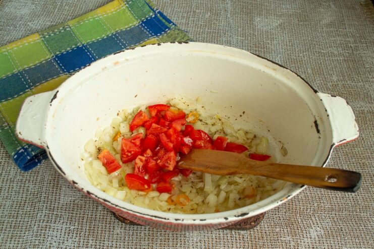 Adding Fresh Tomatoes to the Vegetable Base Diced tomatoes being added to the sautéed vegetables in the roasting pan.
