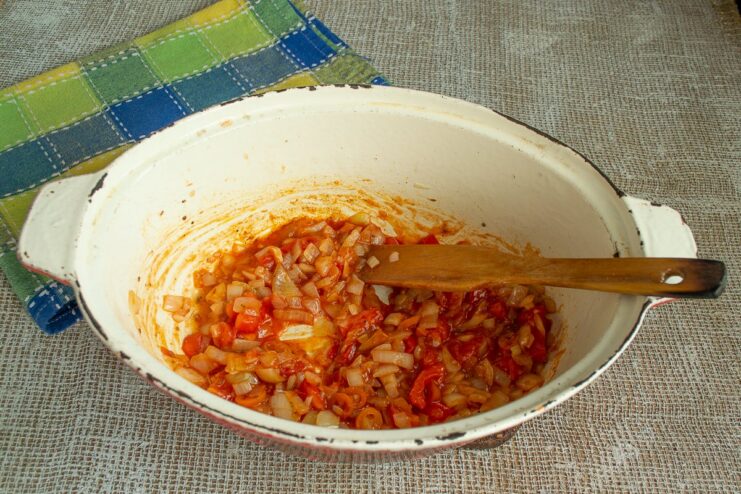 Creating a Rich Tomato Base with Ketchup and Paprika Ketchup and paprika being added to the tomato and vegetable mixture in the pan.