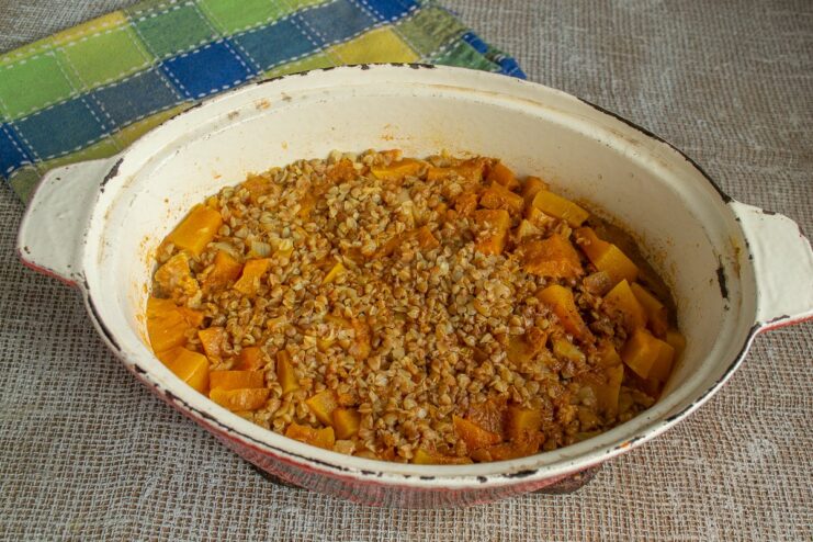Baking the Grechka po-kupecheski Until Tender and Flavorful A covered roasting pan being placed into a preheated oven.