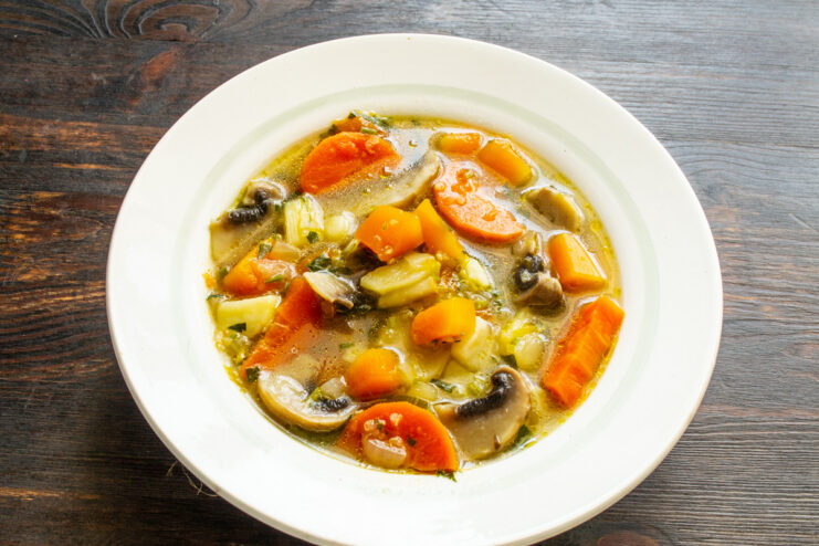 Serving the Deliciously Hot Soup Serving the hot, ready-to-eat mushroom soup with pumpkin and quinoa into bowls.