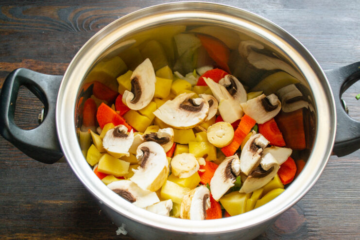 Adding Earthy Mushrooms to the Soup Sliced champignon mushrooms being added to the pot with other vegetables.