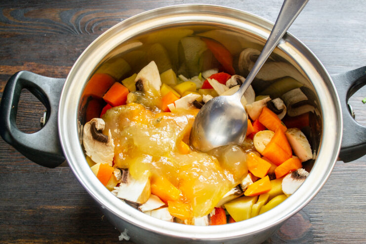 Pouring in the Broth to Simmer Chicken broth being poured into the pot with all the chopped vegetables.