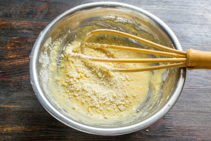 Using Breadcrumbs for Fluffy Fritters Adding breadcrumbs to the fritter batter in a glass bowl to achieve a fluffy texture.