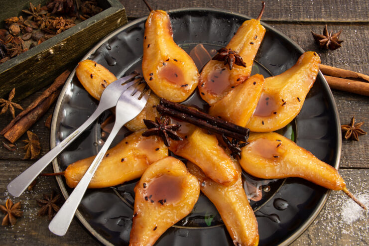 A serving dish with poached Pears in Cognac, drizzled with a dark, glossy syrup.