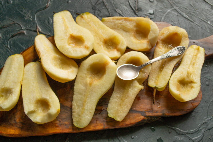 Step 2: Coring the Pears Neatly Using a small metal spoon to scoop the core and seeds out of a halved pear.