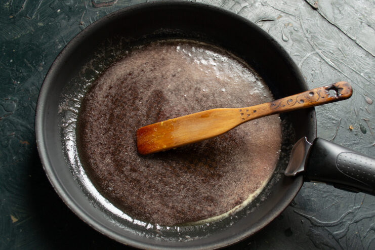 Step 3: Making the Simple Syrup for Poaching Sugar and water being heated in a black skillet to create a clear syrup.