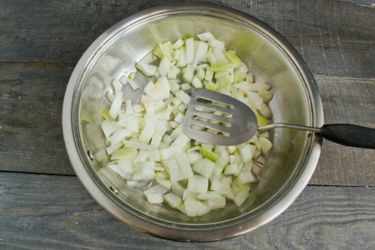 Sautéing chopped onion and garlic until translucent to build the flavor base Chopped onion and garlic being sautéed in a hot pan with butter and oil.