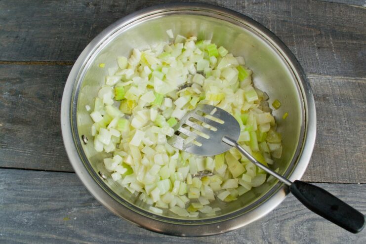 Adding diced celery to the sautéed onions for more flavor and texture Diced celery being added to the pan with sautéed onions.