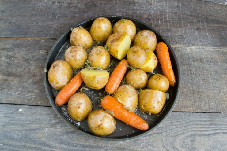 Parboiling potatoes and carrots before roasting them to perfection Parboiled potatoes and carrots in a baking dish, seasoned with herbs.