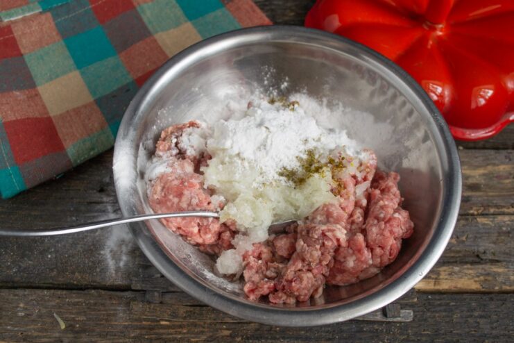Adding cornstarch to bind the meatballs Cornstarch being sprinkled into the bowl with the meatball mixture.