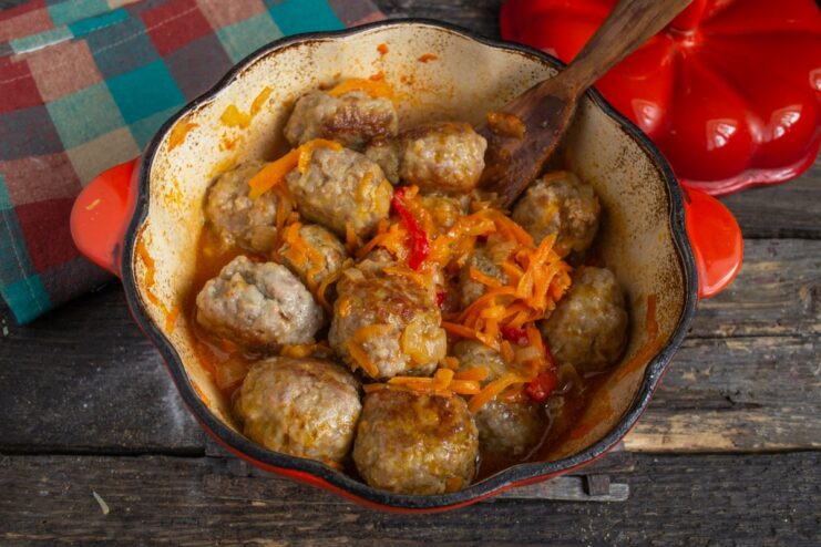 Letting the meatballs simmer in the sauce to absorb flavors Meatballs simmering in the vegetable sauce in a covered skillet.