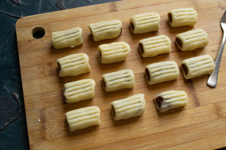 Creating decorative grooves on the cookies with a fork Using a fork to press shallow lines onto the top of an unbaked Nascondini cookie.