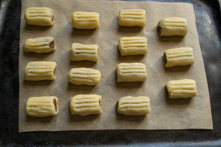 Arranging Nascondini cookies on a baking sheet Unbaked Nascondini cookies arranged on a baking sheet lined with parchment paper.