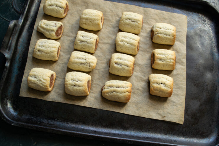 Baking the Nascondini cookies until golden Golden-brown Nascondini cookies baking in the oven on a baking sheet.