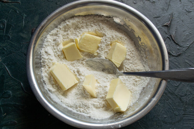 Cubing cold butter for the shortbread dough Cold butter cut into small cubes in a bowl with flour.