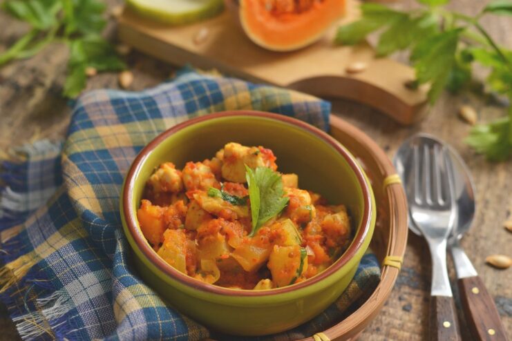 A bowl of ready-to-eat autumn stew with zucchini, pumpkin, and chicken, garnished with fresh herbs.