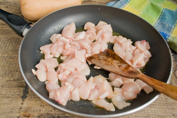 Searing the chicken pieces until golden brown to lock in the juices. Cubed chicken fillet pieces being fried in a skillet.