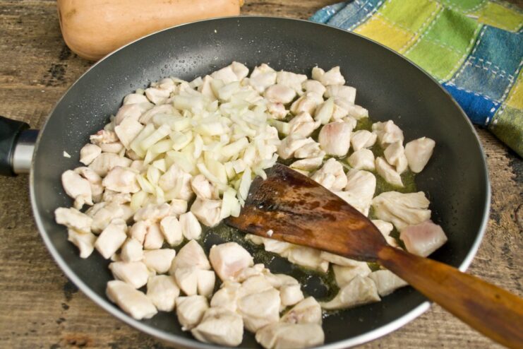 Sautéing chopped onion with the chicken until translucent. Adding chopped onions to the skillet with the seared chicken.