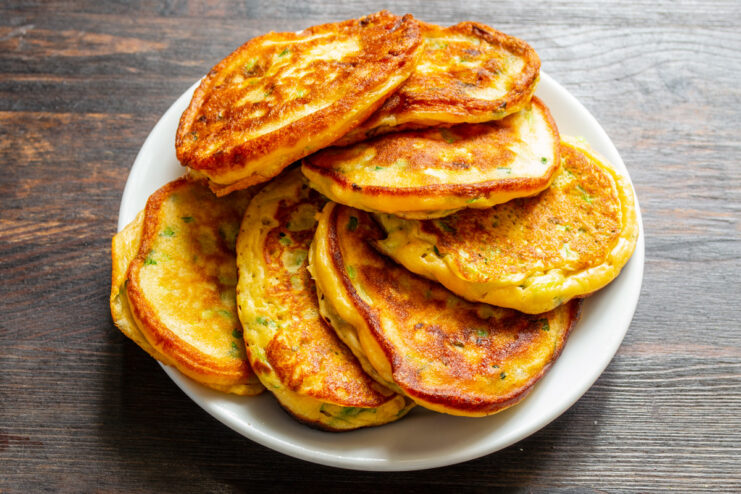 Hot and Ready Zucchini Fritters with Lentil Flour A stack of freshly fried zucchini and lentil flour fritters on a plate, ready to serve.