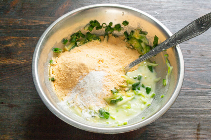 Adding Lentil Flour to the Zucchini Batter Lentil flour being added to the bowl with zucchini and other ingredients.