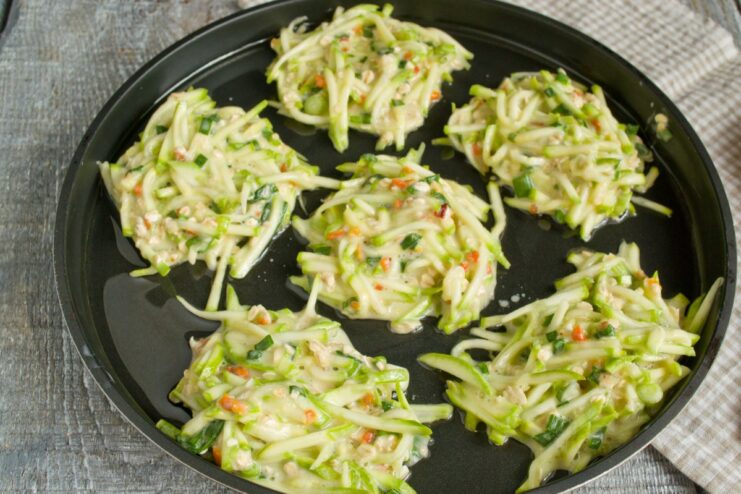 Time to Cook: Spooning Fritter Batter into a Hot Pan Spoonfuls of zucchini fritter batter being placed into a hot, oiled frying pan.